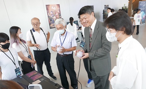 中華電信處長與北科大設計學院院長吳可久體驗學生作品「和諧」。