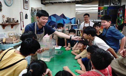 北科大、政大實小合作「城市蜂巢」木工營隊,北科大李昊哲老師引領學生辨識木材,包括手中的「綠檀木」,屬於會沉入水底的特殊樹種。