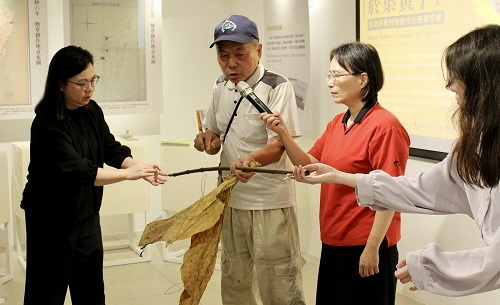 資深菸農黃先生（中）於北科大「彼時・菸葉黃了！」示範綁菸葉的訣竅。（攝影：王映涵）